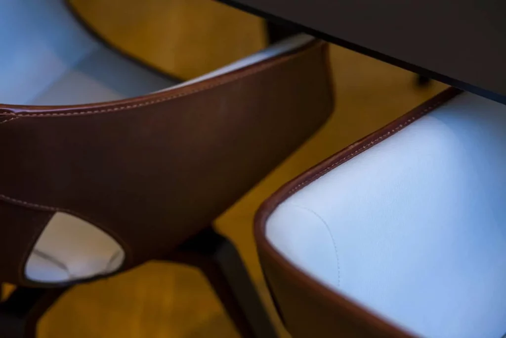 Nahaufnahme von modernen Holzstühlen mit weißem Lederbezug