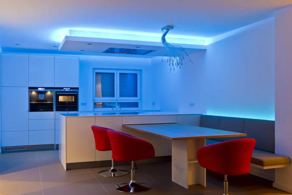 Moderne Küche mit blauer LED-Beleuchtung und roten Stühlen