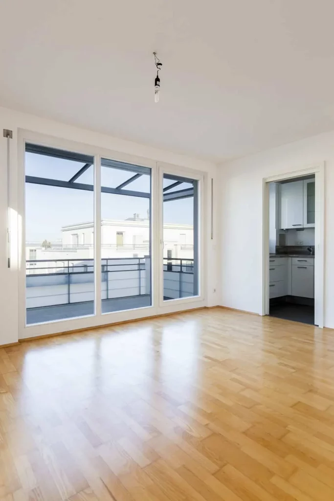 Helle, leere Wohnung mit Balkon und Parkettboden