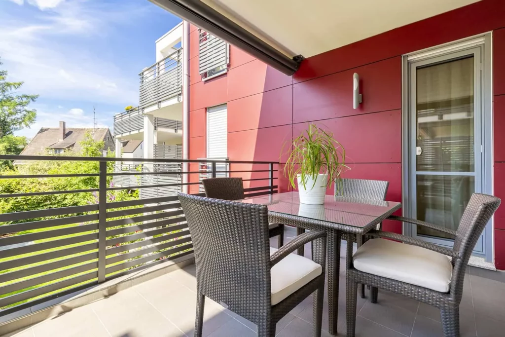 Moderne Balkon mit roter Fassade und Sitzmöbel
