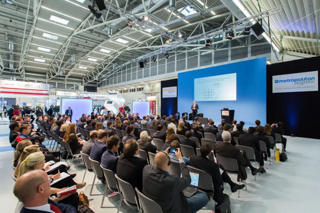 Konferenz mit Vortrag und vielen Teilnehmern in einer Messehalle