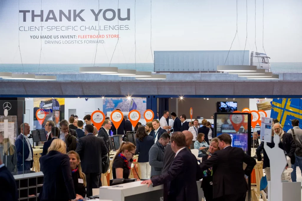 Besucher auf einer Logistikmesse diskutieren neue Innovationen