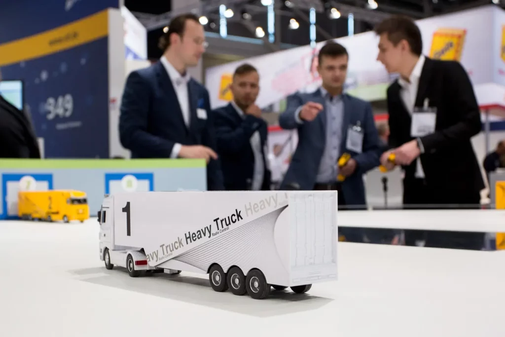 Modell eines Schwerlastwagens auf einer Messe mit vier geschäftlichen Männern im Hintergrund