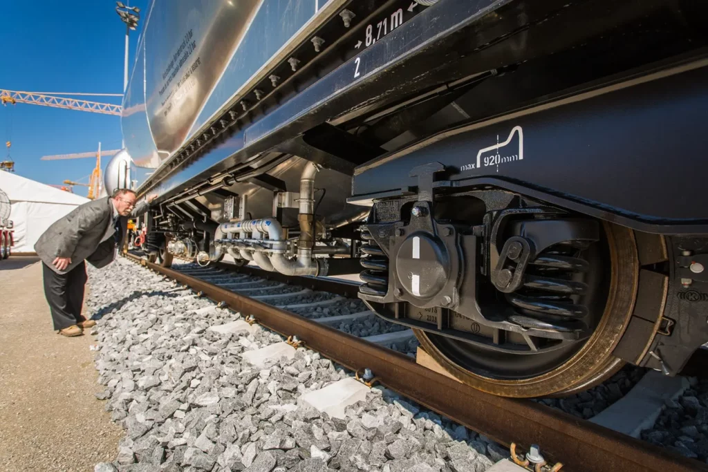 Mann inspiziert moderne Zugwaggon-Räder an einer Gleisstrecke