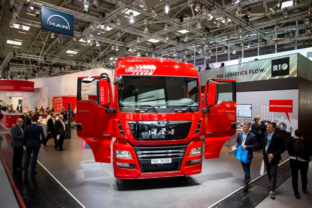 Roter MAN-Lkw auf Automobilausstellung mit Besuchern