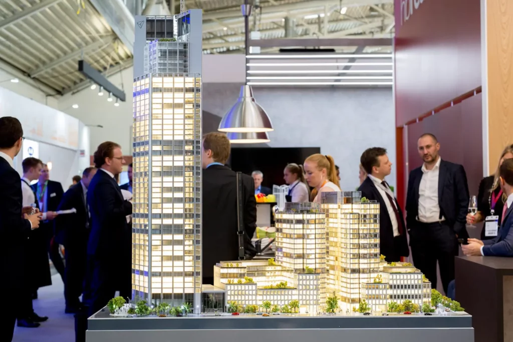 Architekturmodell eines beleuchteten Hochhauskomplexes auf einer Messe