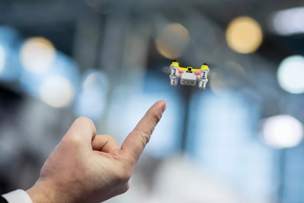 Nahaufnahme einer Drohne, die über einem ausgestreckten Finger schwebt