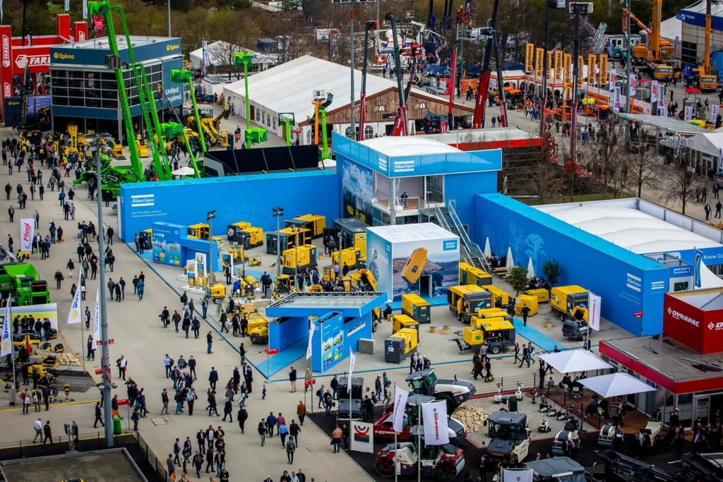 Große Industriemesse mit Menschen und gelben Maschinen im Freien