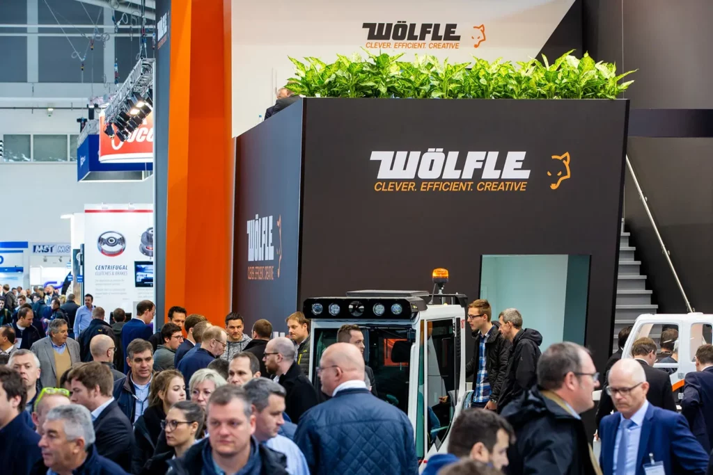 Menschenmenge bei Industriemesse vor Wölfle-Stand mit moderner Präsentation