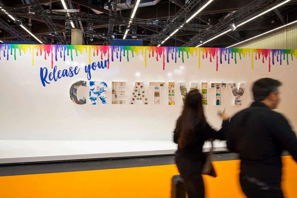 Kreativmesse mit Menschen vor farbenfrohem Wandtext