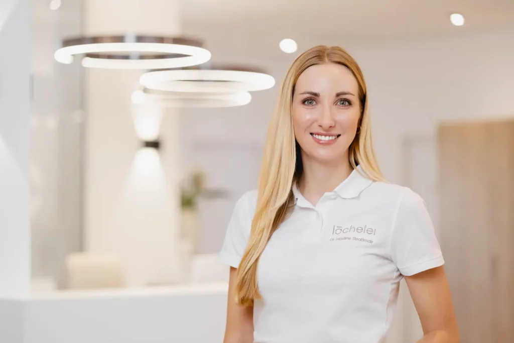 Freundliche Frau in moderner Zahnarztpraxis lächelt in die Kamera