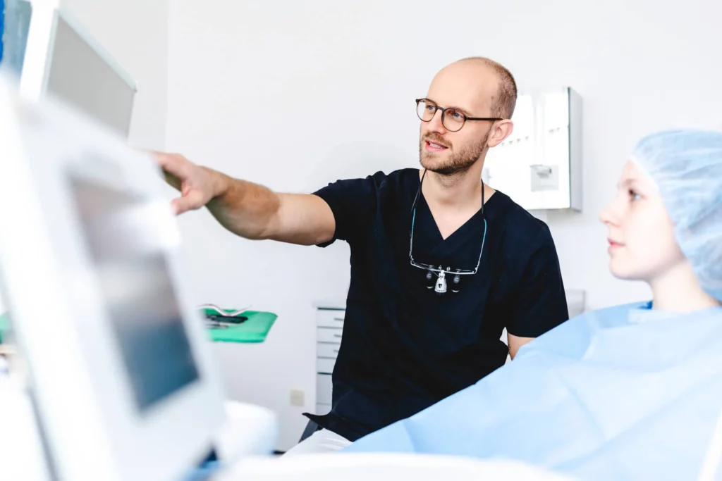 Zahnarzt erklärt Patientin einen Eingriff am Bildschirm