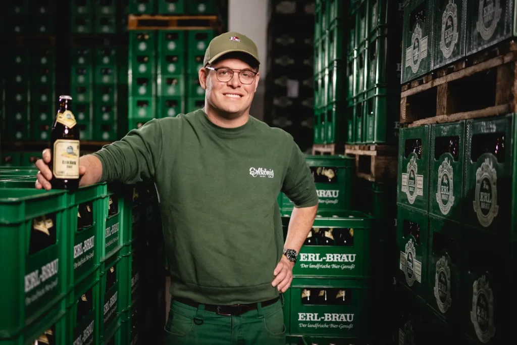 Lächelnder Mann in Brauerei mit Bierkisten von Erl-Bräu