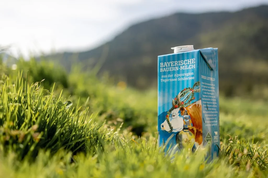 Verpackung Bayerische Bauern-Milch auf Wiese mit Alpenhintergrund