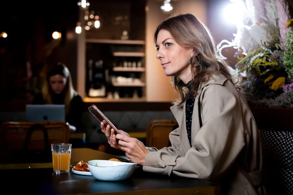 Frau im Café mit Smartphone und Frühstück
