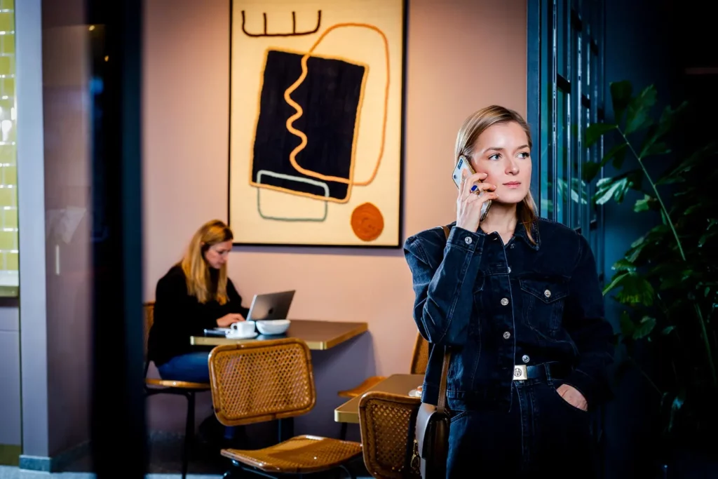 Frau telefoniert in einem stilvollen Café mit Kunst an der Wand