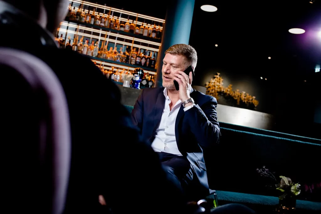 Geschäftsmann im Anzug telefoniert in stilvoller Bar