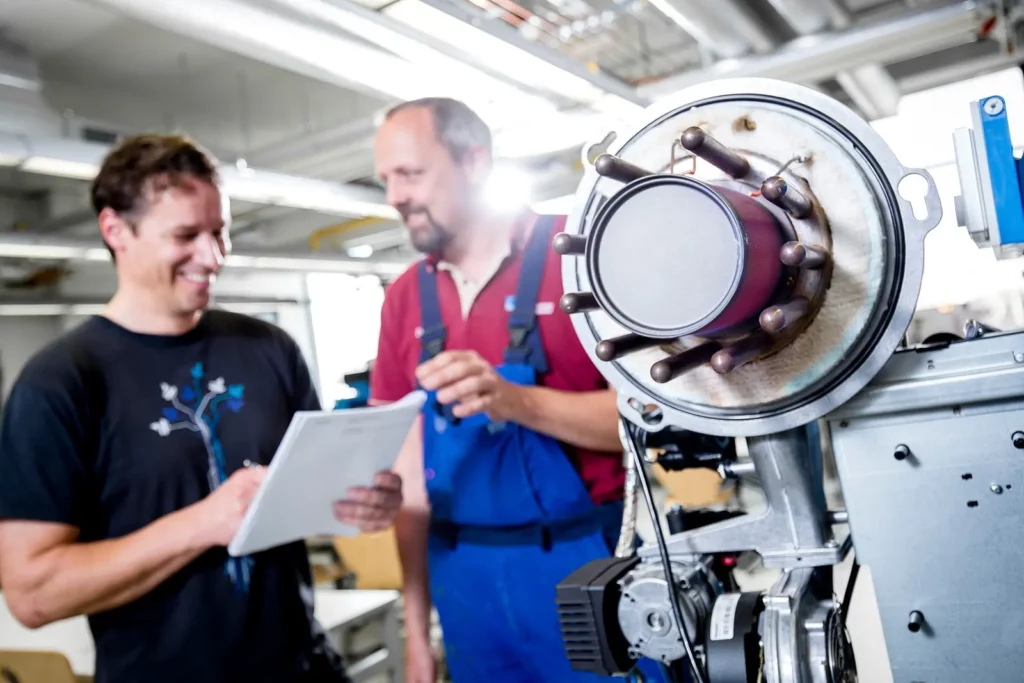 Ingenieure diskutieren in Werkstatt vor Motorkomponente